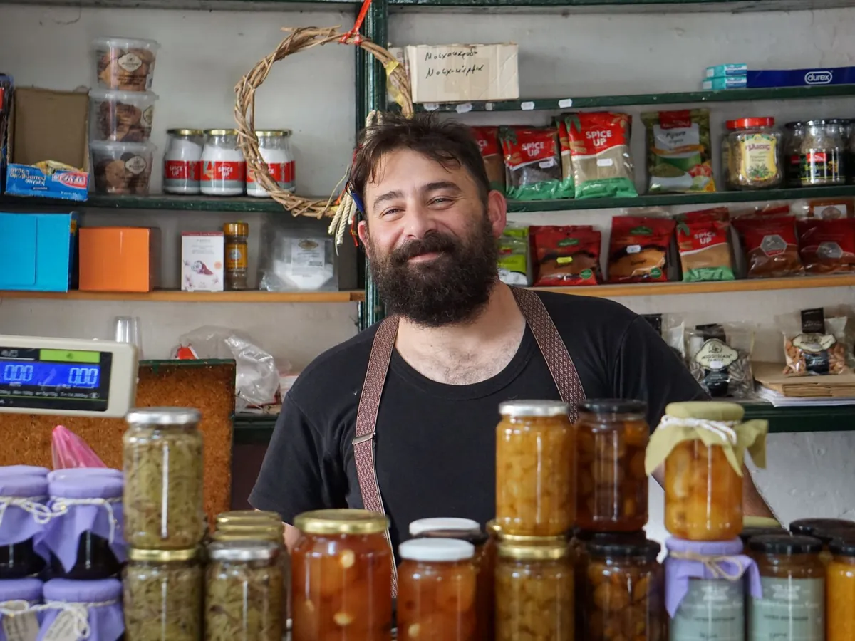 Commerçant souriant derrière son comptoir avec des bocaux de produits artisanaux