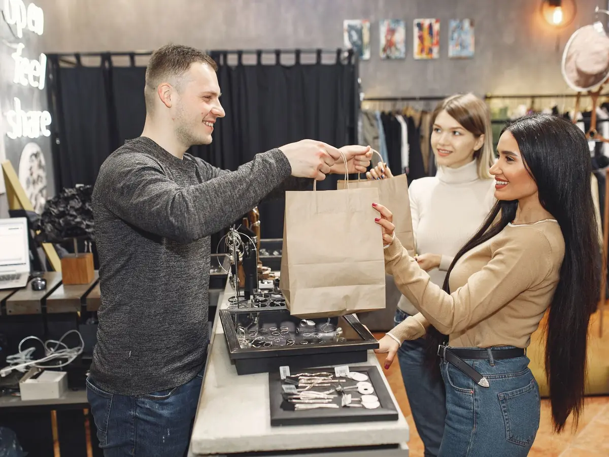 Vendeur remettant un sac à une cliente au comptoir d'une boutique