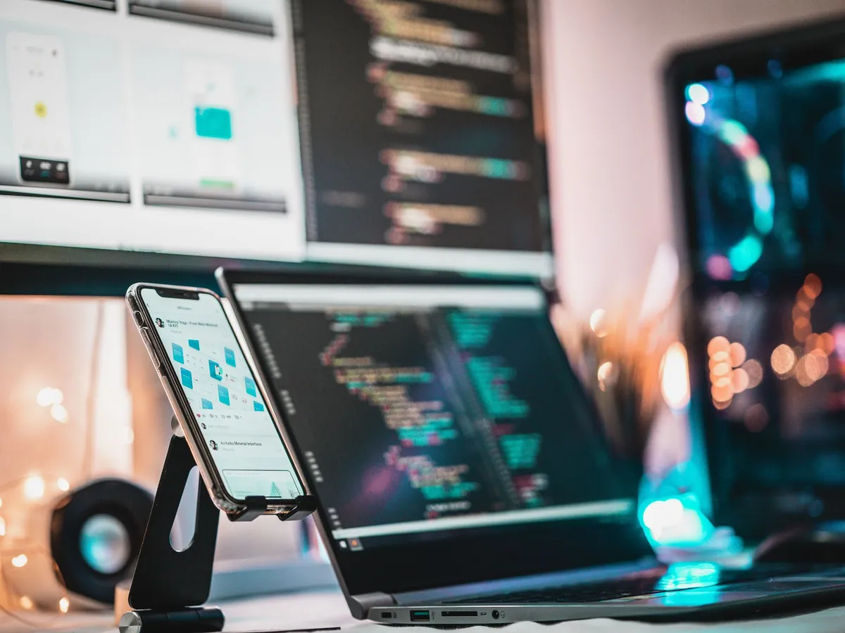 Poste de travail avec écrans de code et smartphone posé sur un support
