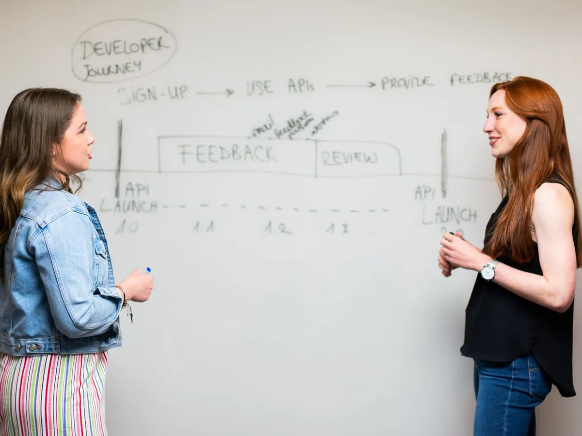Deux collègues discutant devant un tableau blanc où est schématisé un parcours d'automatisation