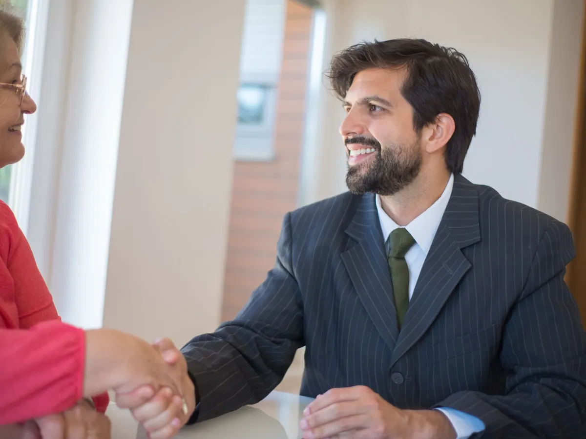 Commercial souriant serrant la main d'une cliente lors d'un rendez-vous