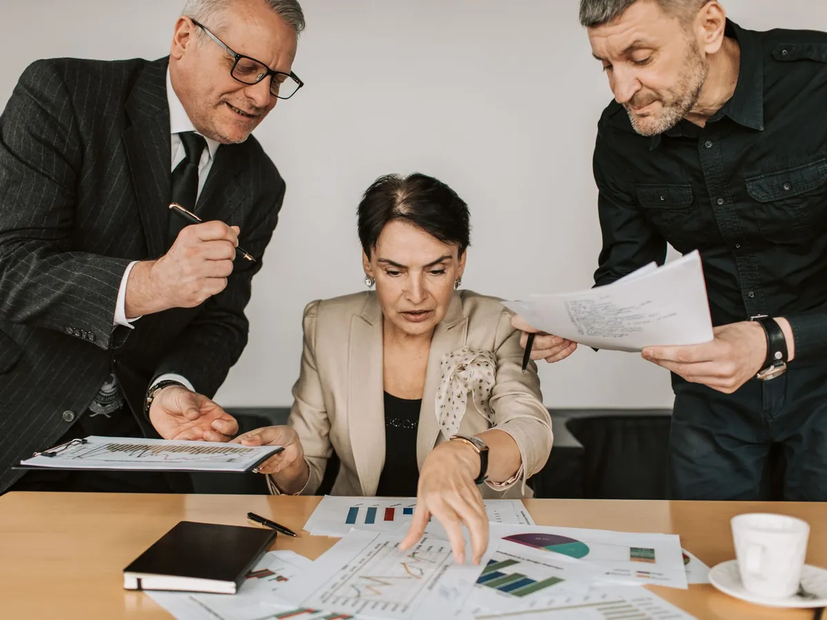 Trois collaborateurs examinant ensemble des rapports financiers et des graphiques