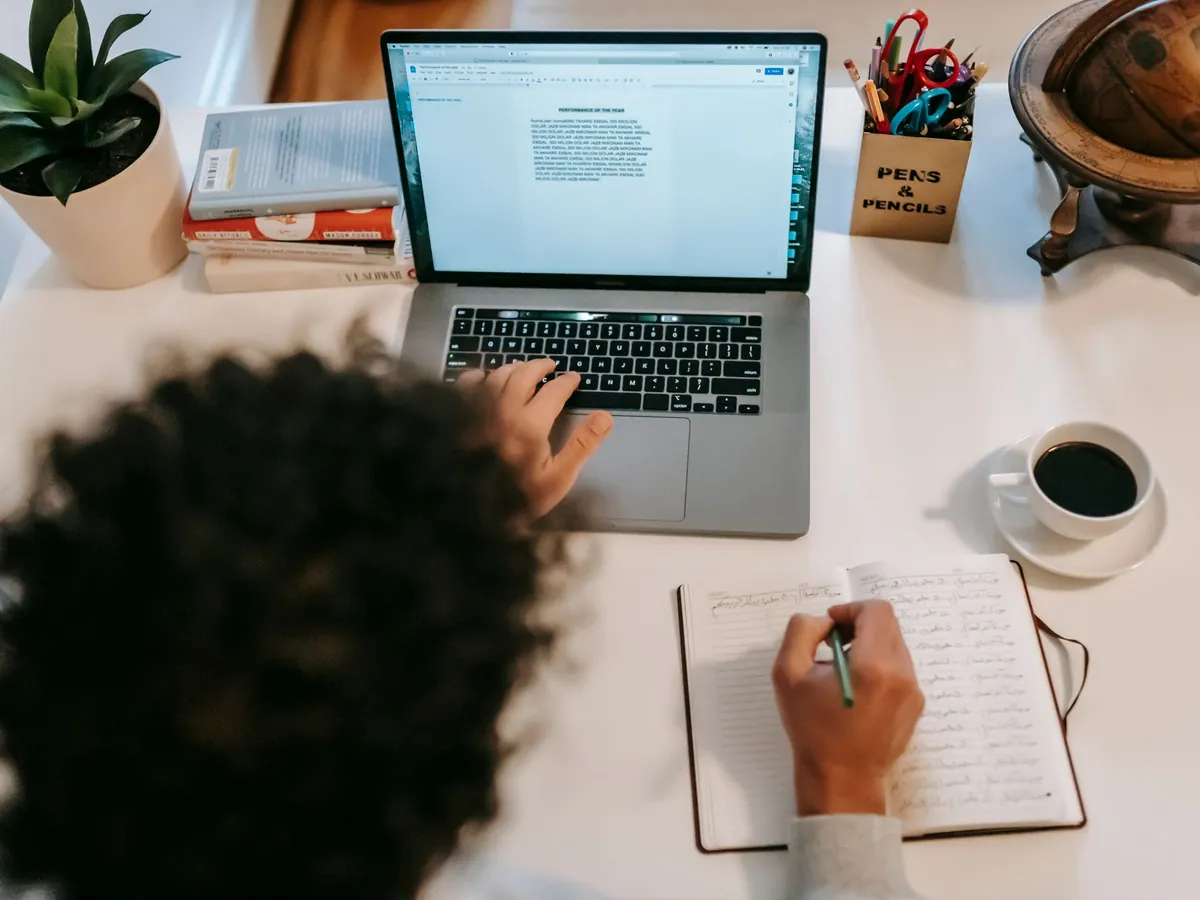 Rédactrice prenant des notes à côté de son ordinateur portable et d'un café