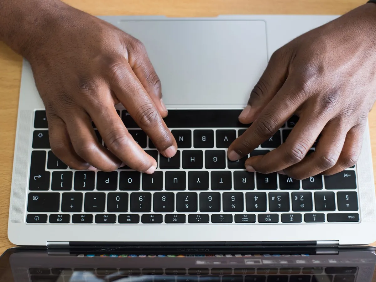 Mains tapant sur le clavier d'un ordinateur portable posé sur un bureau