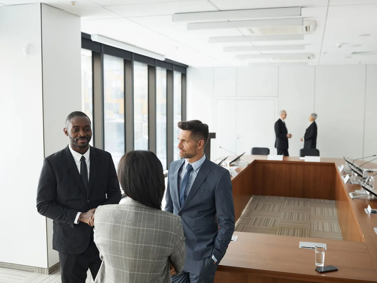Dirigeants en costume discutant dans une salle de conseil lumineuse