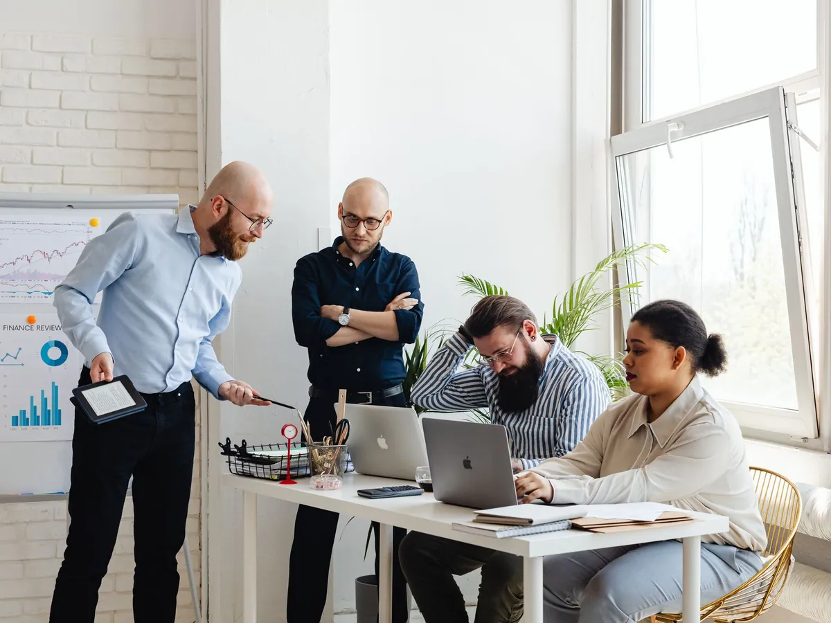Équipe diversifiée discutant de stratégie dans un bureau moderne, avec ordinateurs portables et graphiques