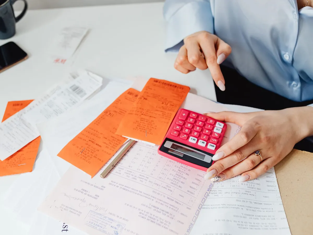 Femme d'affaires calculant des dépenses à partir de tickets de caisse et d'une calculatrice