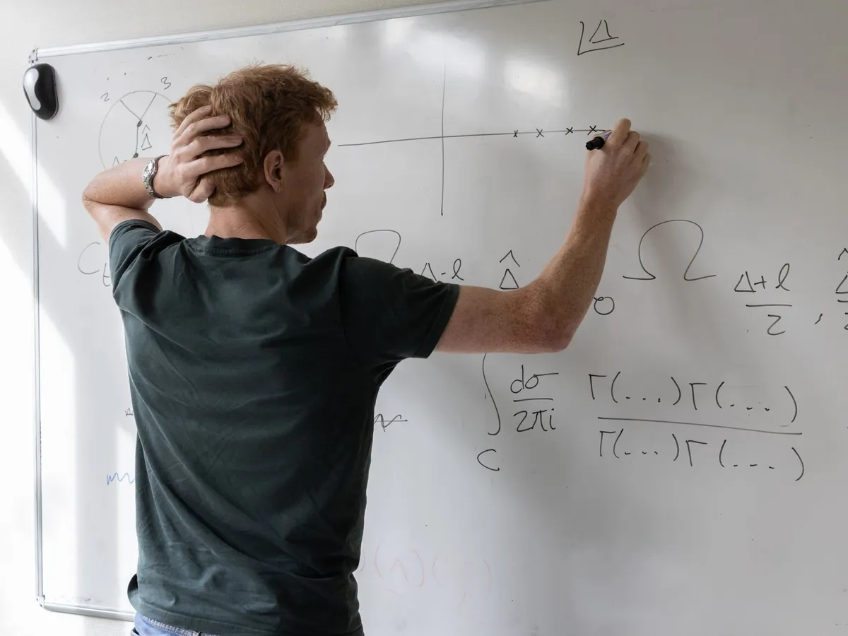 Enseignant écrivant des équations mathématiques au tableau dans une salle de classe