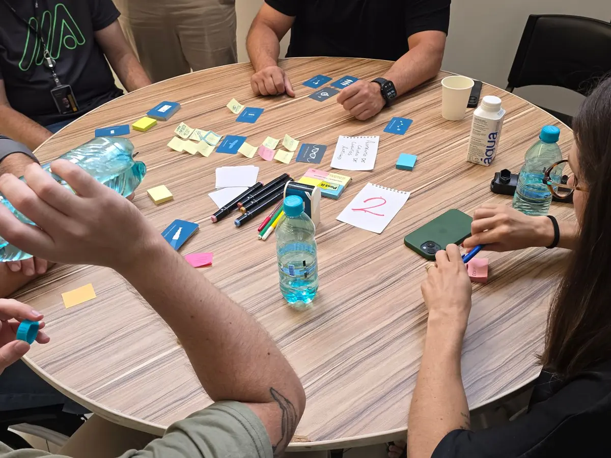 Groupe d'adultes collaborant autour d'une table ronde, post-it et bouteilles d'eau à portée de main