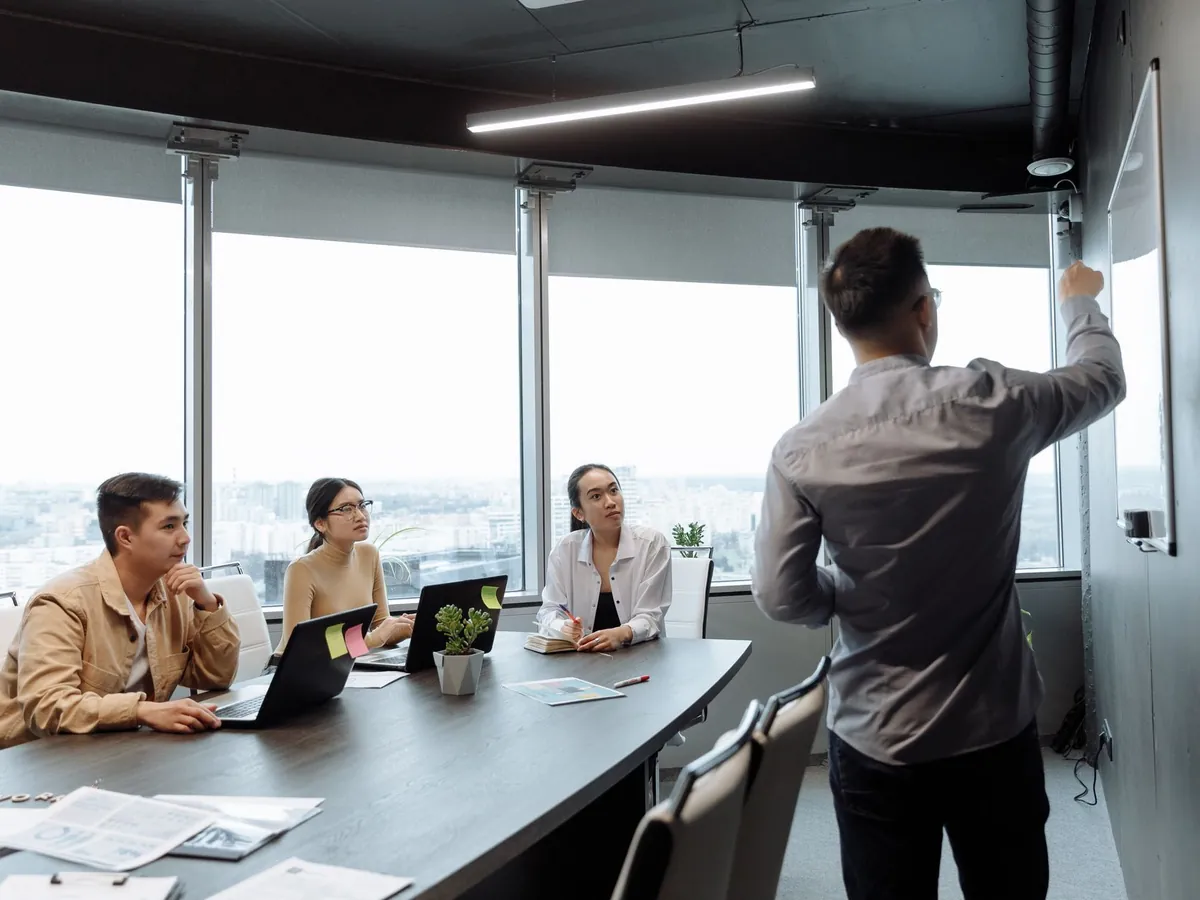 Collègues en salle de réunion, commentant une présentation face à une vue sur la ville