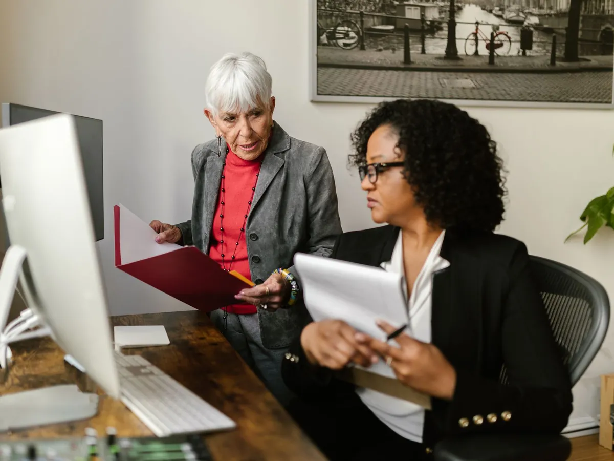 Femmes senior et jeunes femmes collaborant dans un bureau moderne en discutant de documents