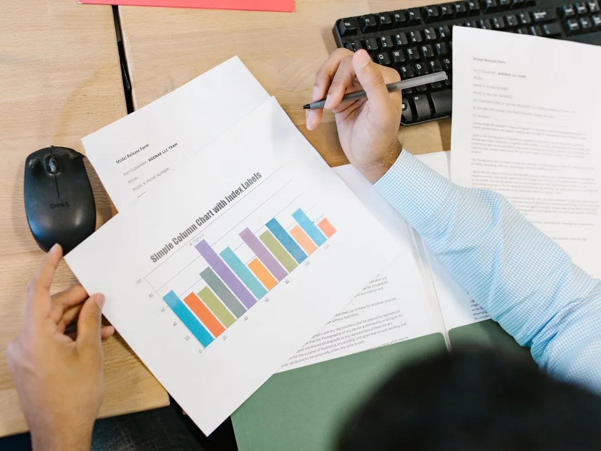 Analyste examinant un graphique à barres coloré et des documents à son bureau, traitement de données
