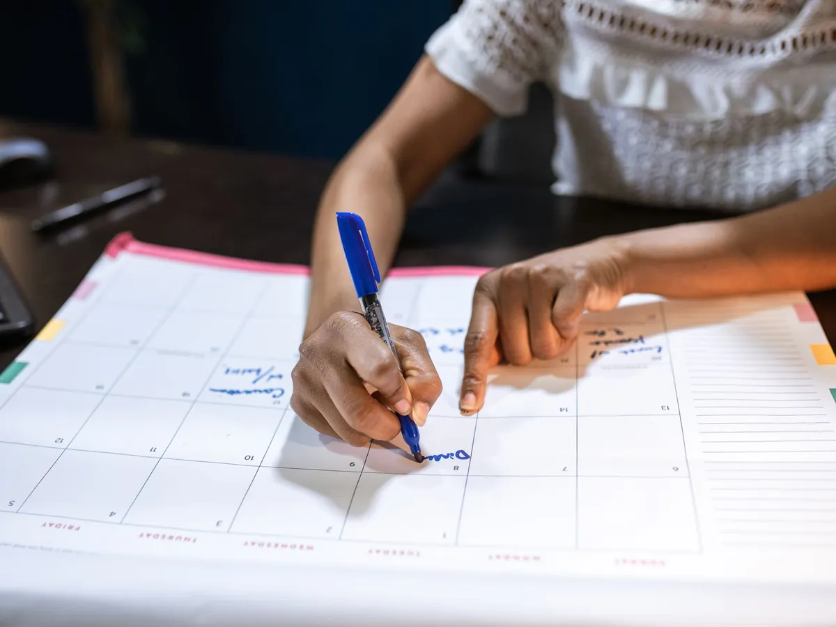 Femme notant des dates importantes sur son calendrier de bureau