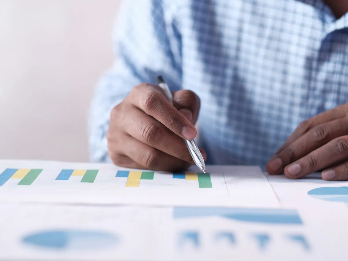 Gros plan de mains analysant des graphiques colorés, illustrant la planification d'entreprise