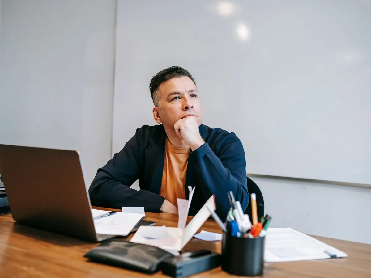 Homme pensif dans un bureau à domicile, concentré sur son travail avec un ordinateur portable