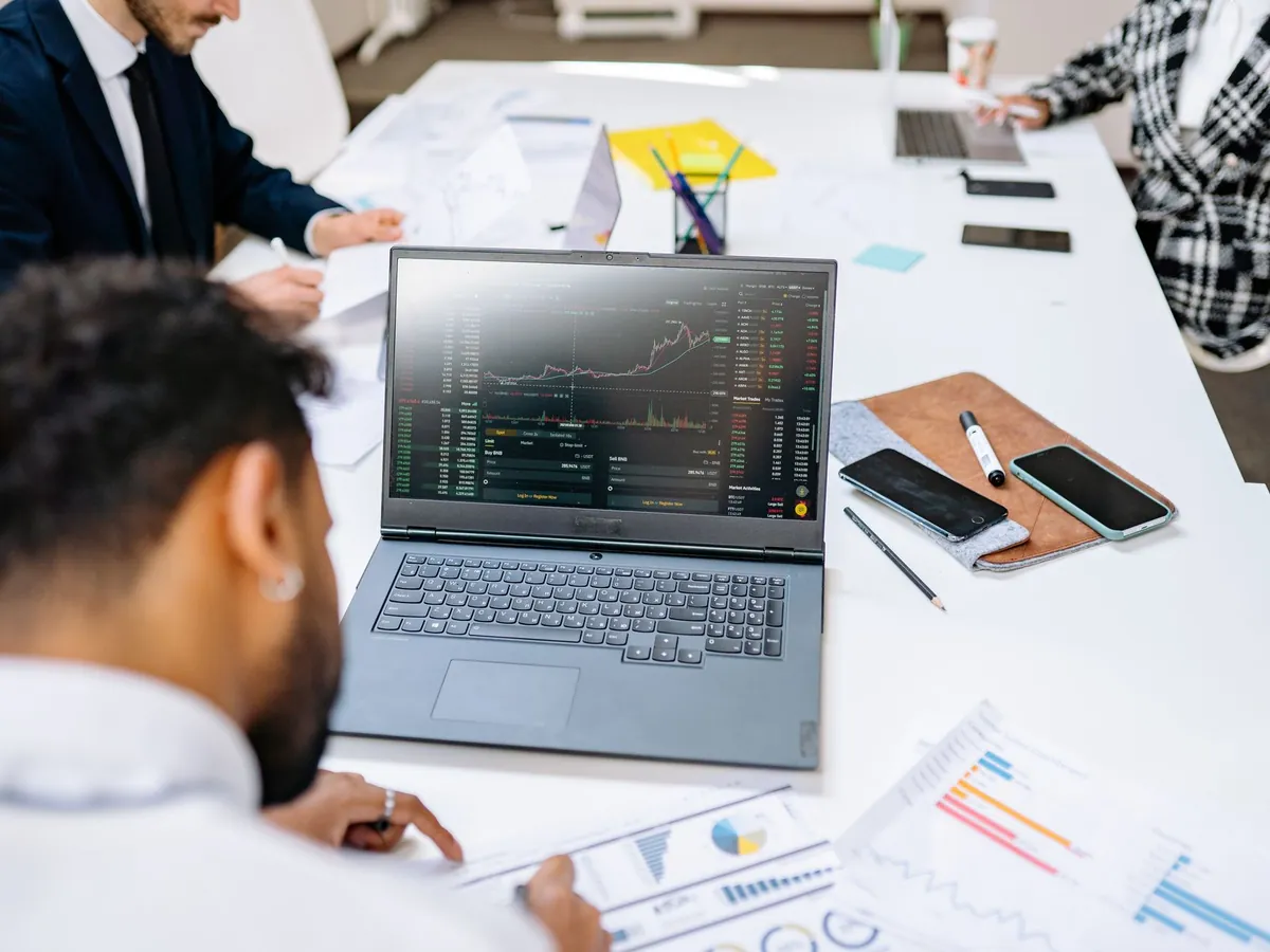 Équipe au bureau, commentant des graphiques financiers affichés sur l'écran d'un ordinateur portable