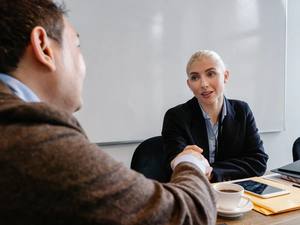 Collègues en tenue élégante se serrant la main dans un espace de travail, après un plan d'affaires abouti