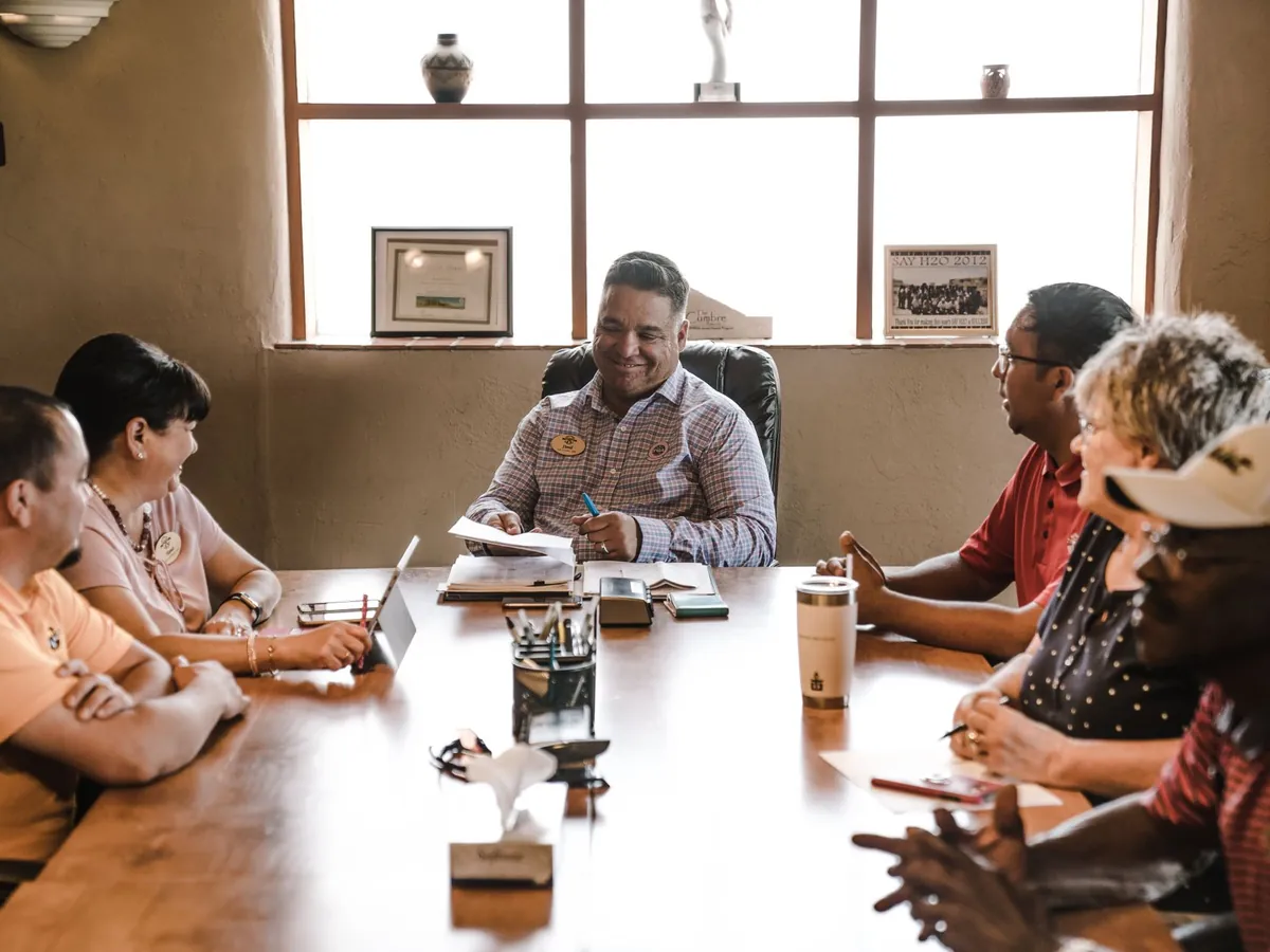 Groupe d'adultes aux profils variés en réunion d'équipe, dans une salle de bureau bien éclairée