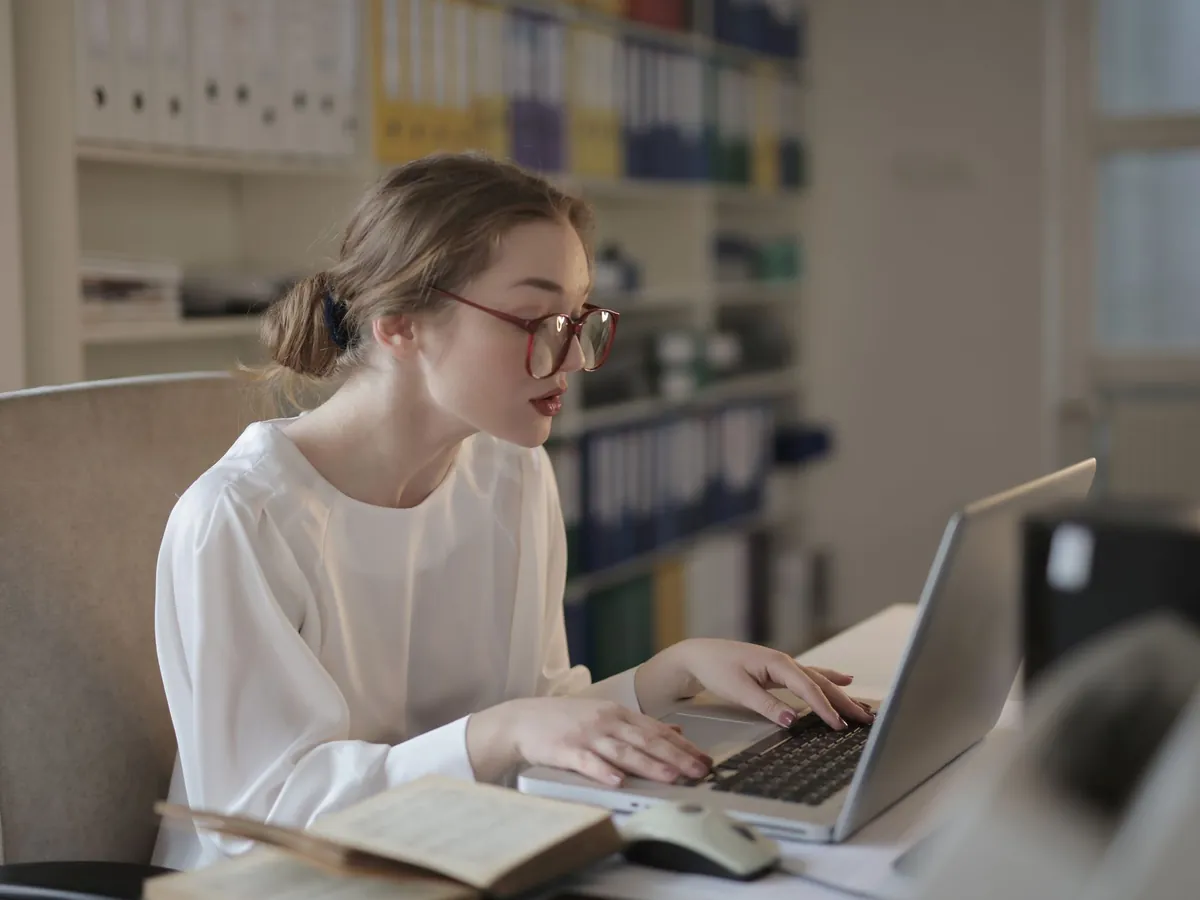 Professionnelle à lunettes travaillant sur un ordinateur portable dans un bureau moderne et organisé