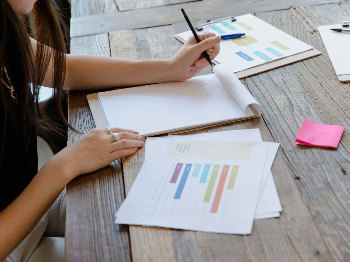 Professionnel dans un espace de travail prenant des notes, entouré de graphiques et de documents