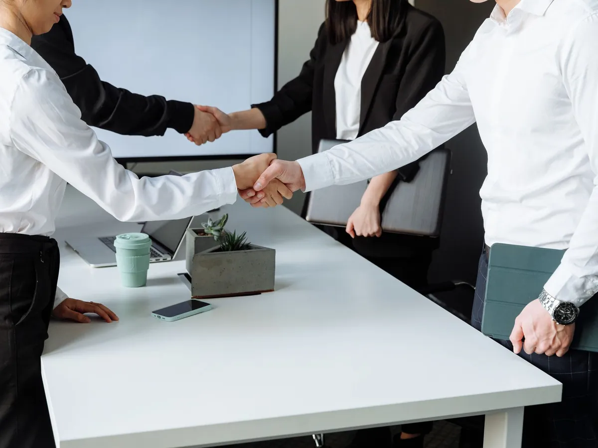 Professionnels d'entreprise se serrant la main sur un accord, autour d'une table moderne