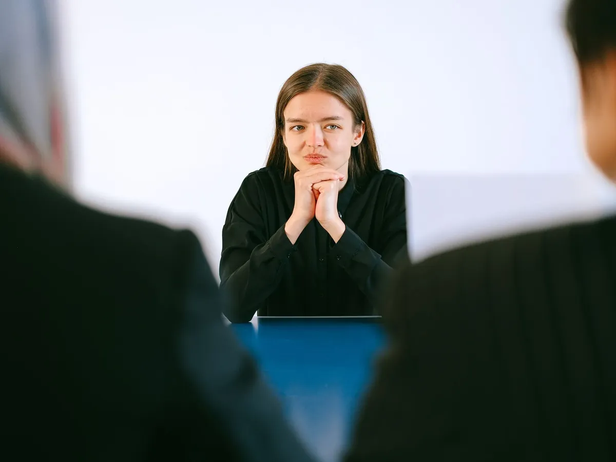 Femme en entretien d'embauche face à deux personnes attablées dans un bureau