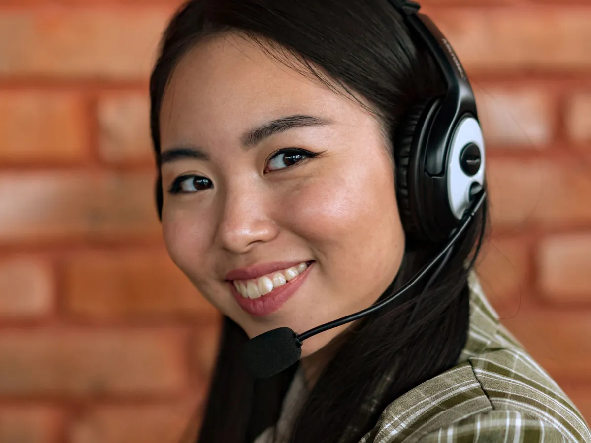 Gros plan d'une jeune femme asiatique au casque, souriante, en intérieur