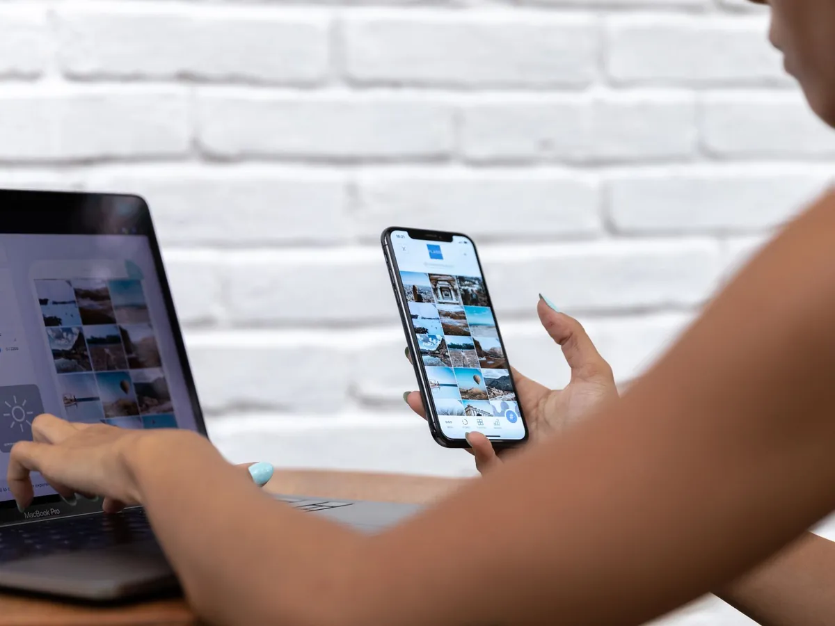 Femme en télétravail avec ordinateur portable et smartphone, concentrée sur des contenus sociaux