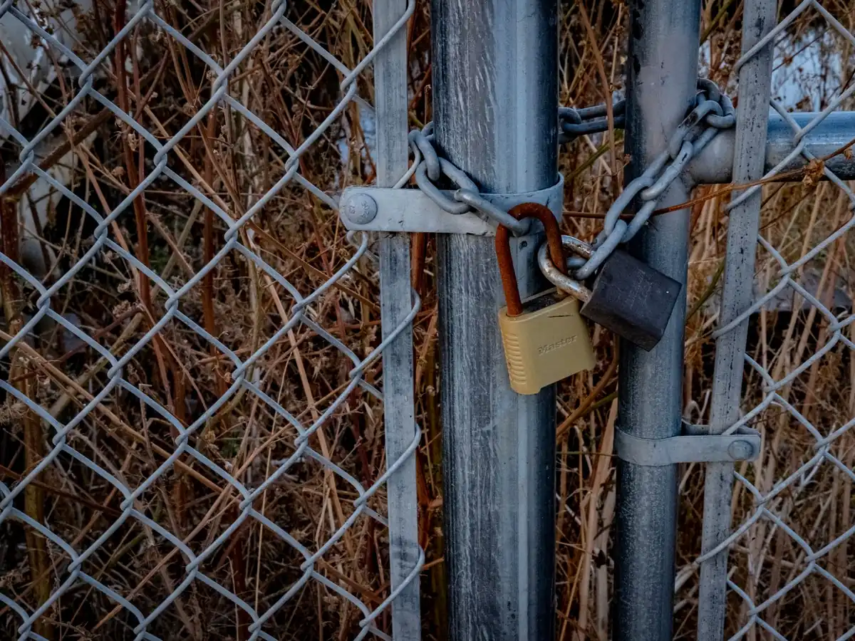 Gros plan sur une clôture grillagée sécurisée par des cadenas, symbole de haute sécurité en extérieur