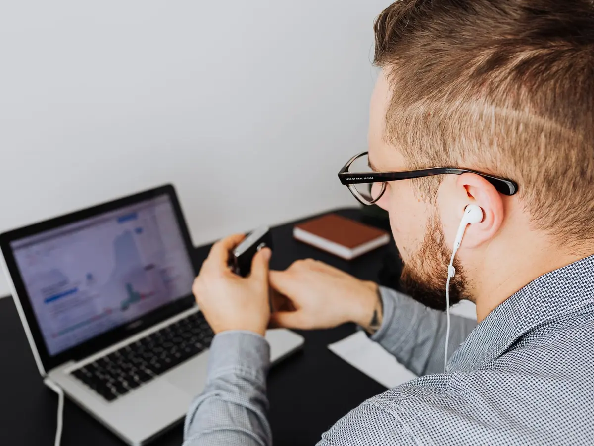 Professionnelle utilisant un ordinateur portable avec graphiques, écouteurs aux oreilles, au bureau