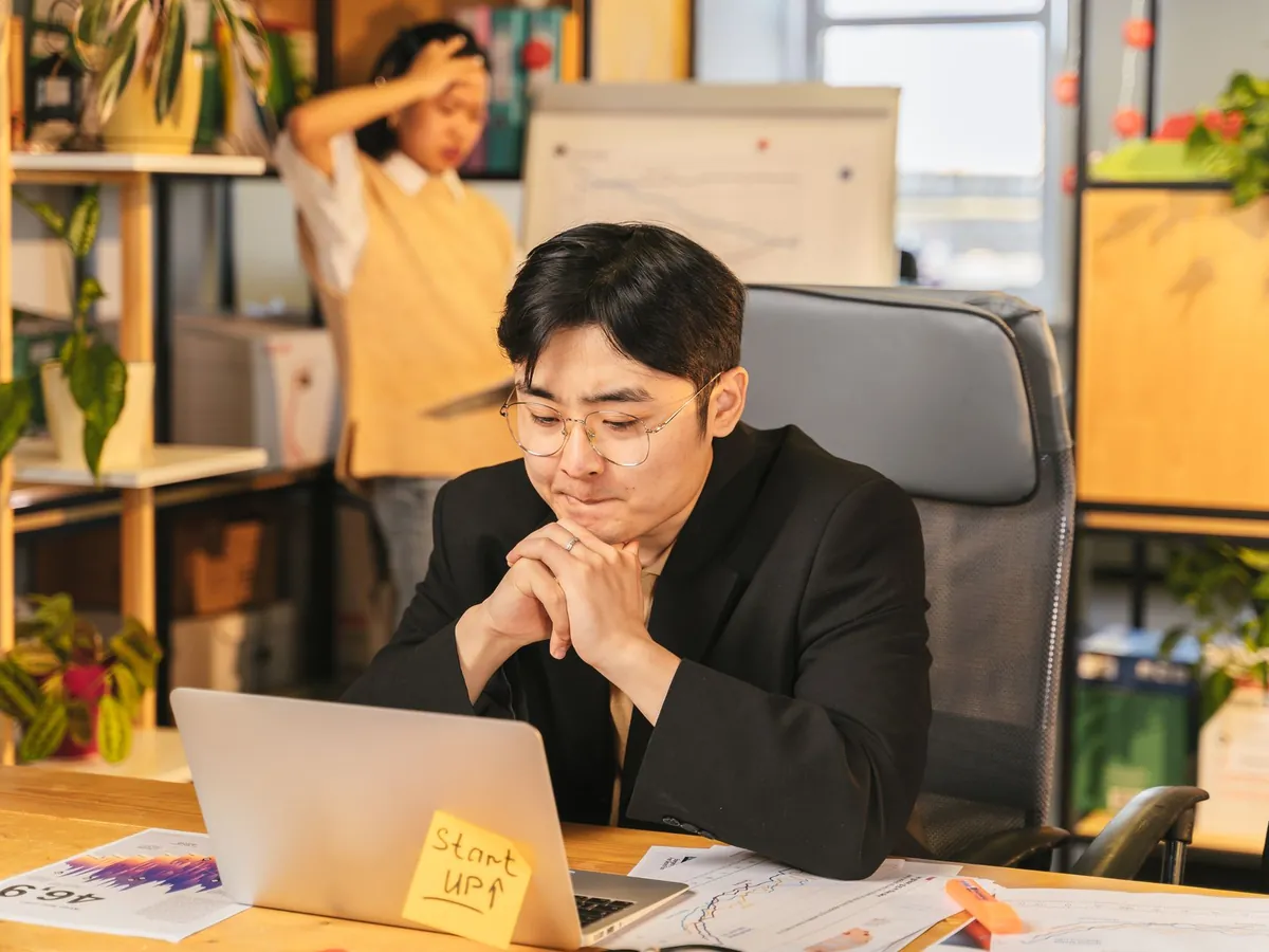Jeune professionnel absorbé dans ses pensées en travaillant sur un ordinateur portable, bureau moderne