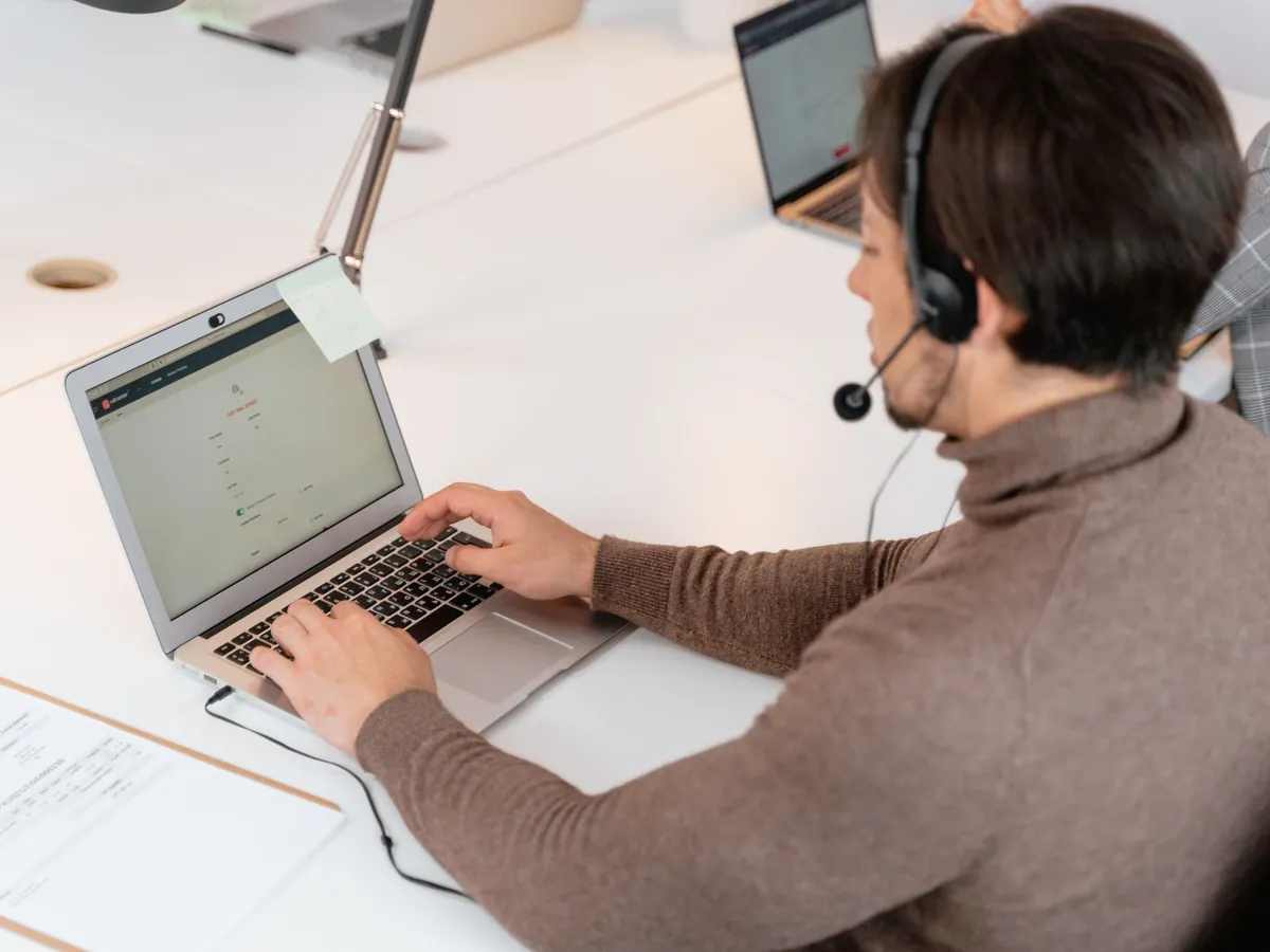Agent de centre d'appels avec casque, travaillant sur ordinateur portable dans un bureau moderne