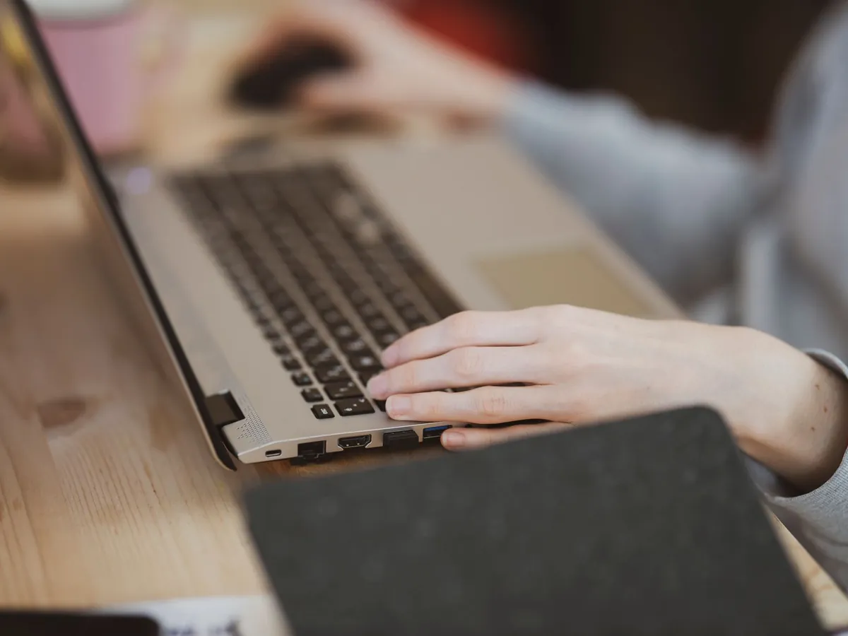 Gros plan d'une personne tapant sur un ordinateur portable, centré sur la main et le clavier