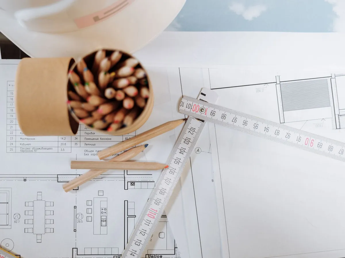 Crayons de couleur et règle posés sur des plans d'architecte
