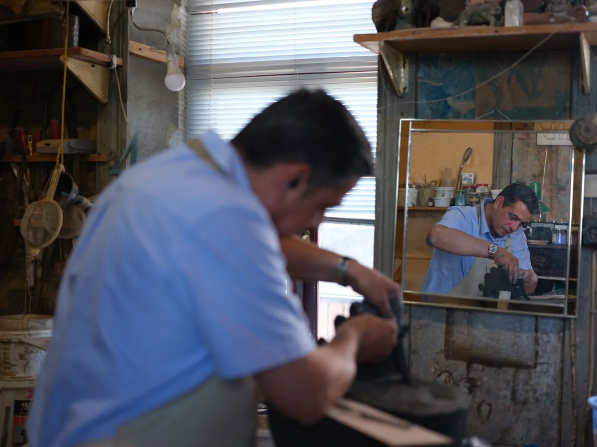 Artisan concentré sur son travail dans un atelier rustique, capturé dans le reflet d'un miroir