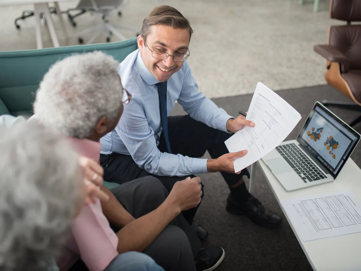 Conseiller financier échangeant sur des documents avec des clients, lors d'une séance de conseil