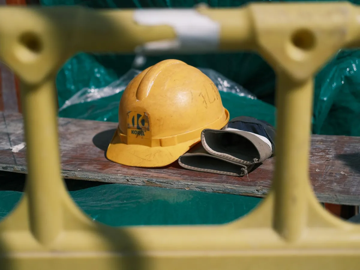 Gros plan d'un casque de chantier jaune posé sur un établi