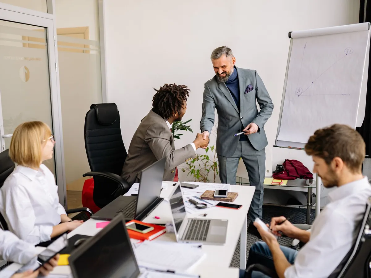 Collègues se serrant la main pendant une réunion d'entreprise, signe de partenariat et d'accord