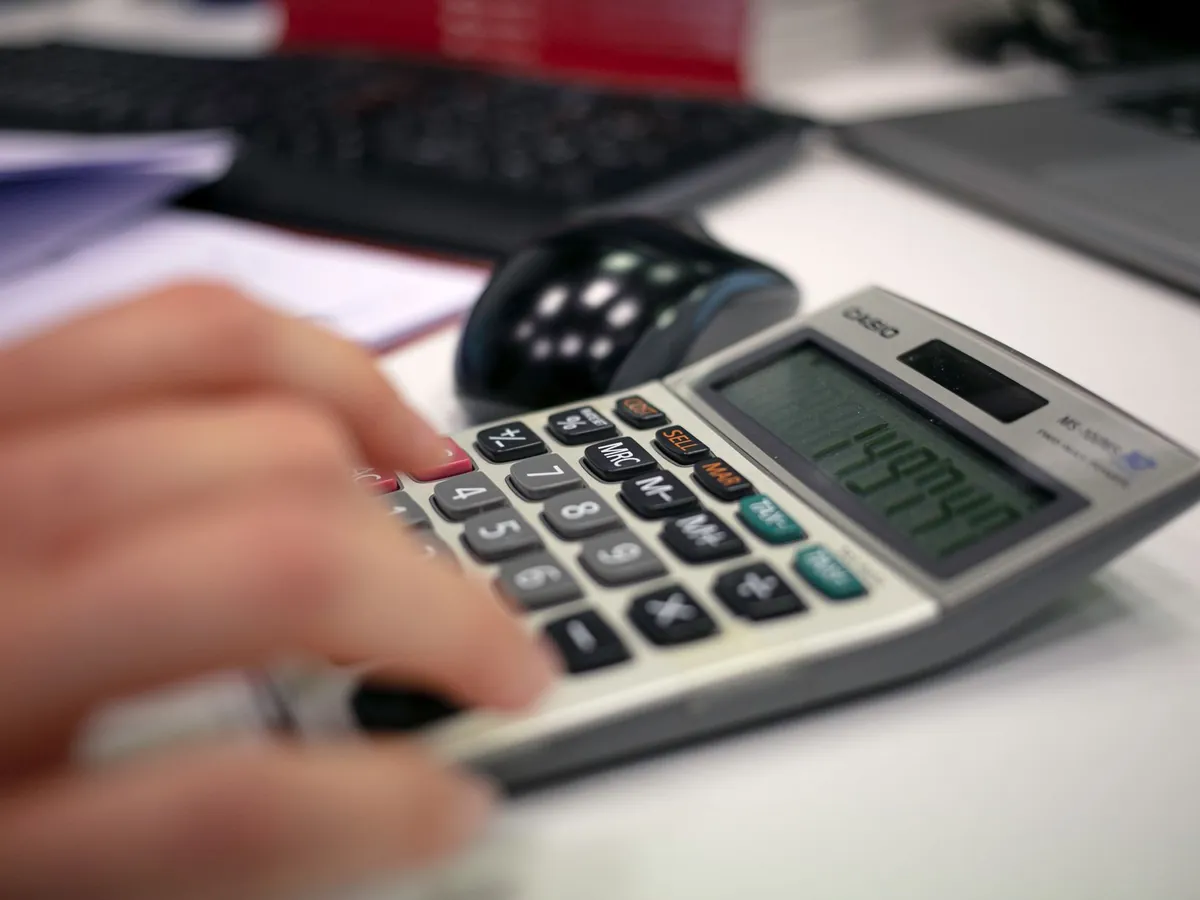 Gros plan d'une main utilisant une calculatrice sur un bureau