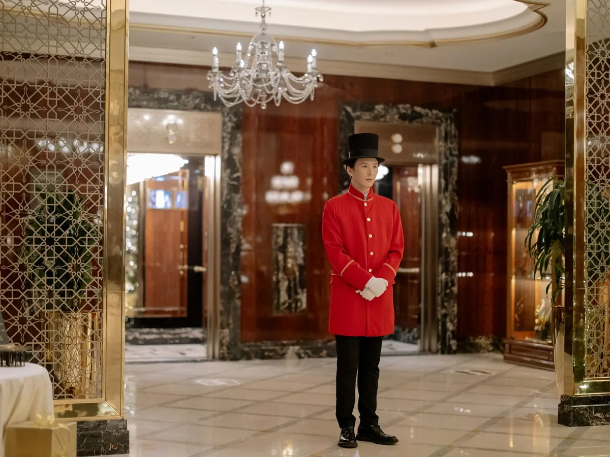 Hall d'hôtel élégant, avec un portier en uniforme prêt à accueillir les clients