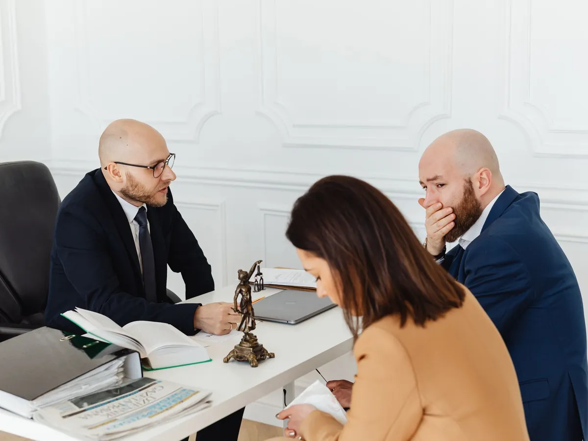 Consultation juridique sérieuse dans un bureau professionnel, avec trois adultes
