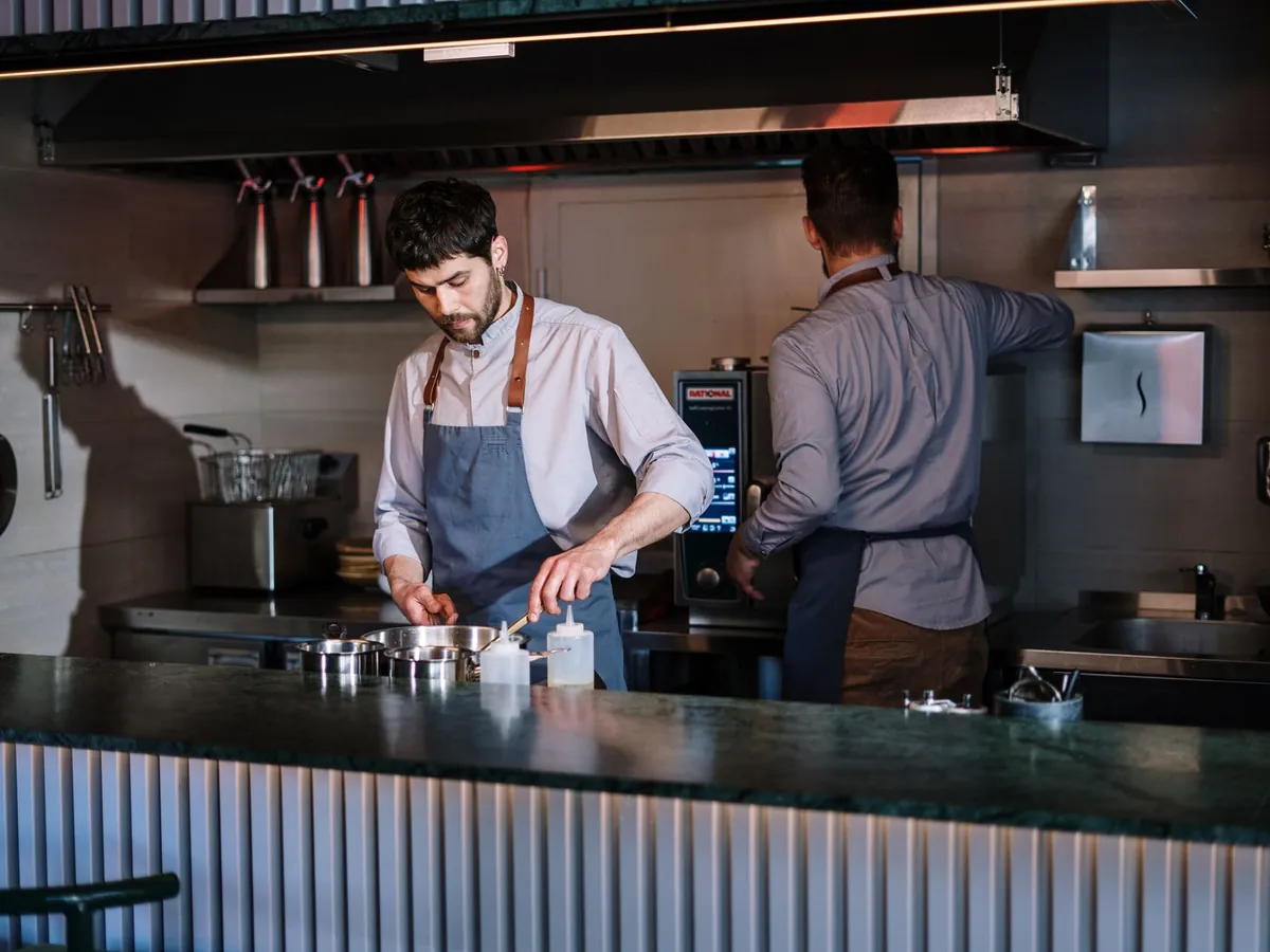 Deux chefs préparant des plats en cuisine ouverte, dans un restaurant moderne