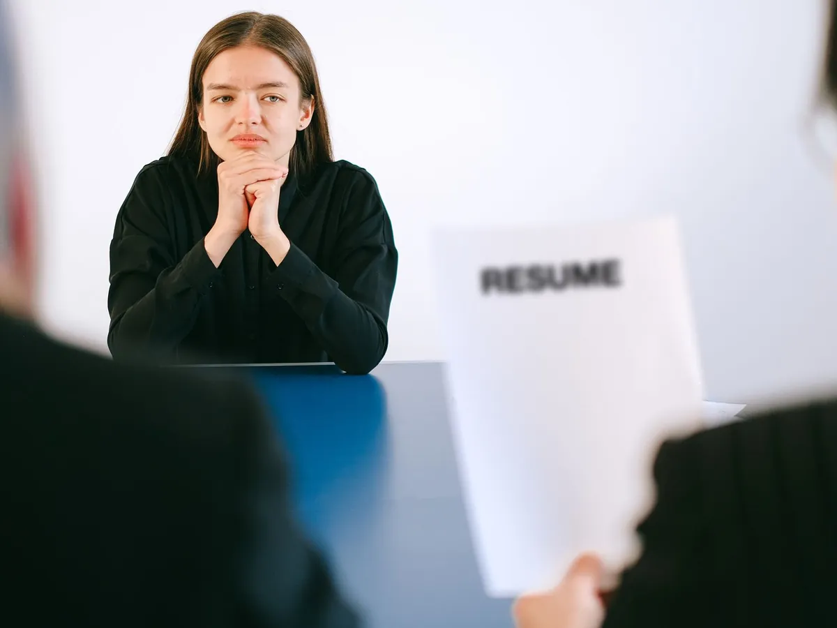 Femme en entretien d'embauche face à deux recruteurs, son CV à la main