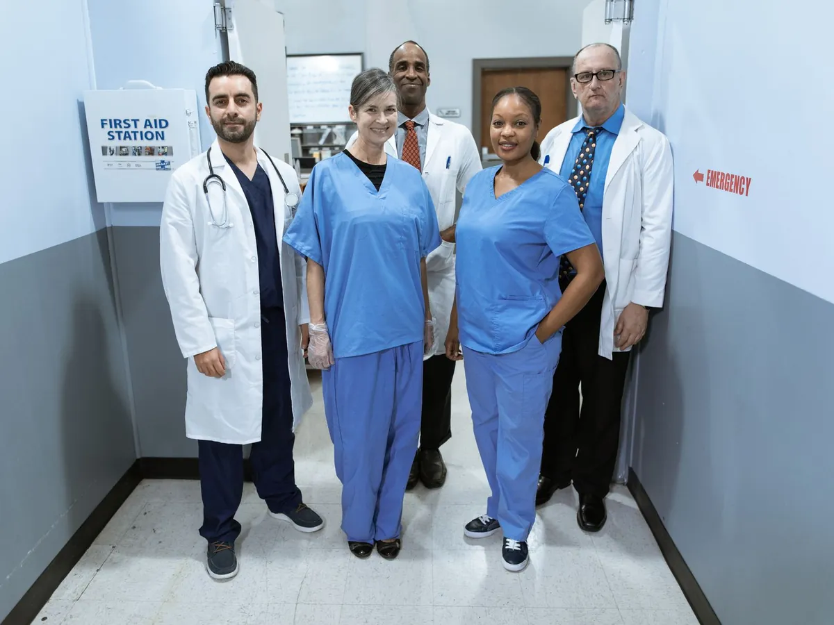 Groupe de professionnels de santé aux profils variés, souriants dans un couloir d'hôpital