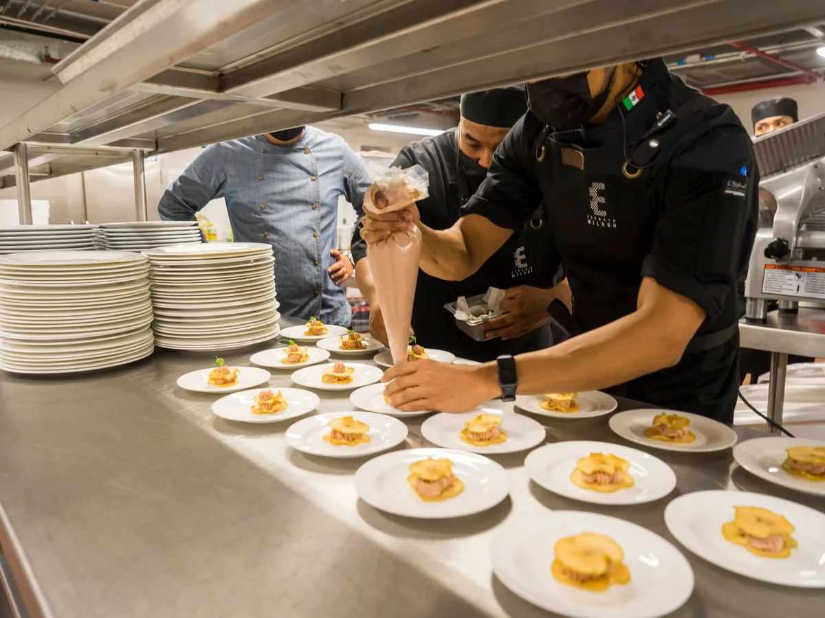 Chefs dressant méticuleusement des assiettes gourmandes dans une cuisine professionnelle animée