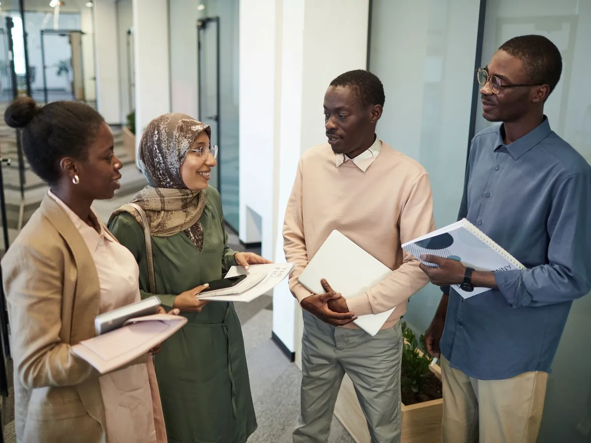 Collègues échangeant dans un couloir de bureau avec des documents