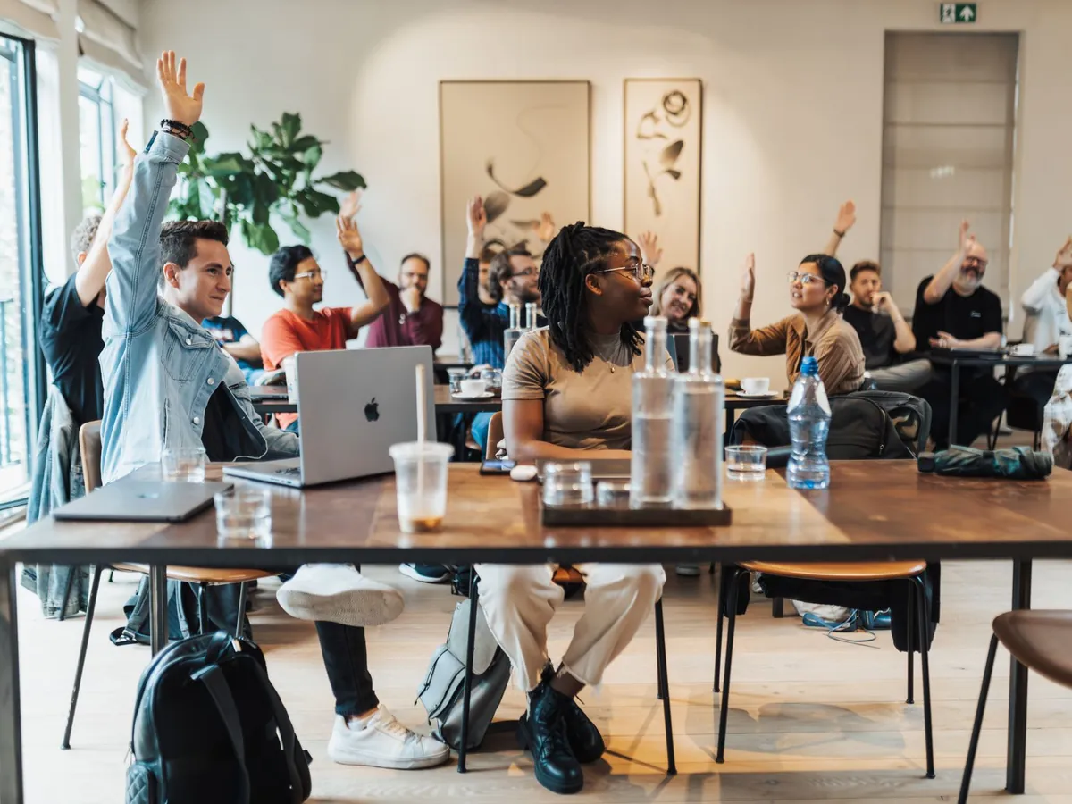 Participants de plusieurs entreprises levant la main lors d'une formation collective