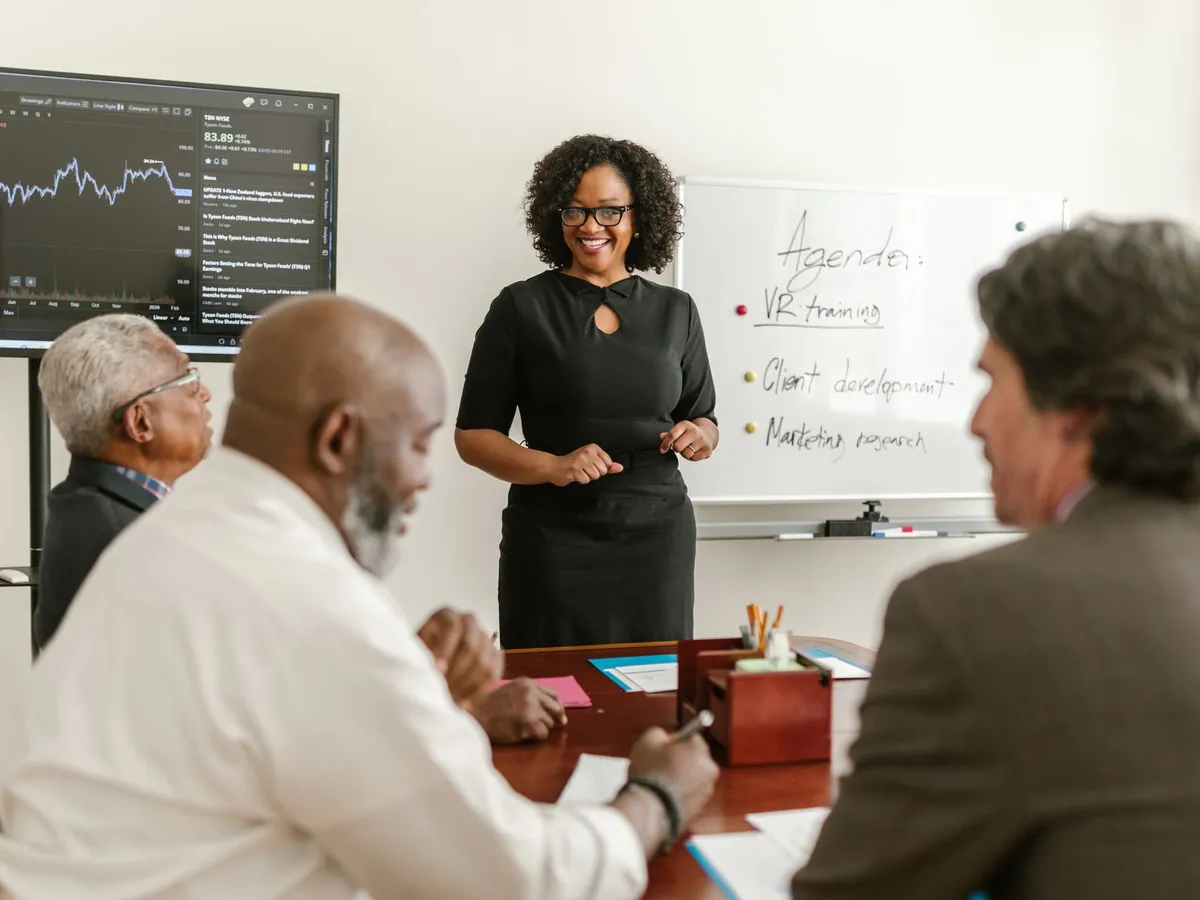 Professionnels en réunion d'affaires, échangeant sur des stratégies et plans de formation, graphiques à l'appui