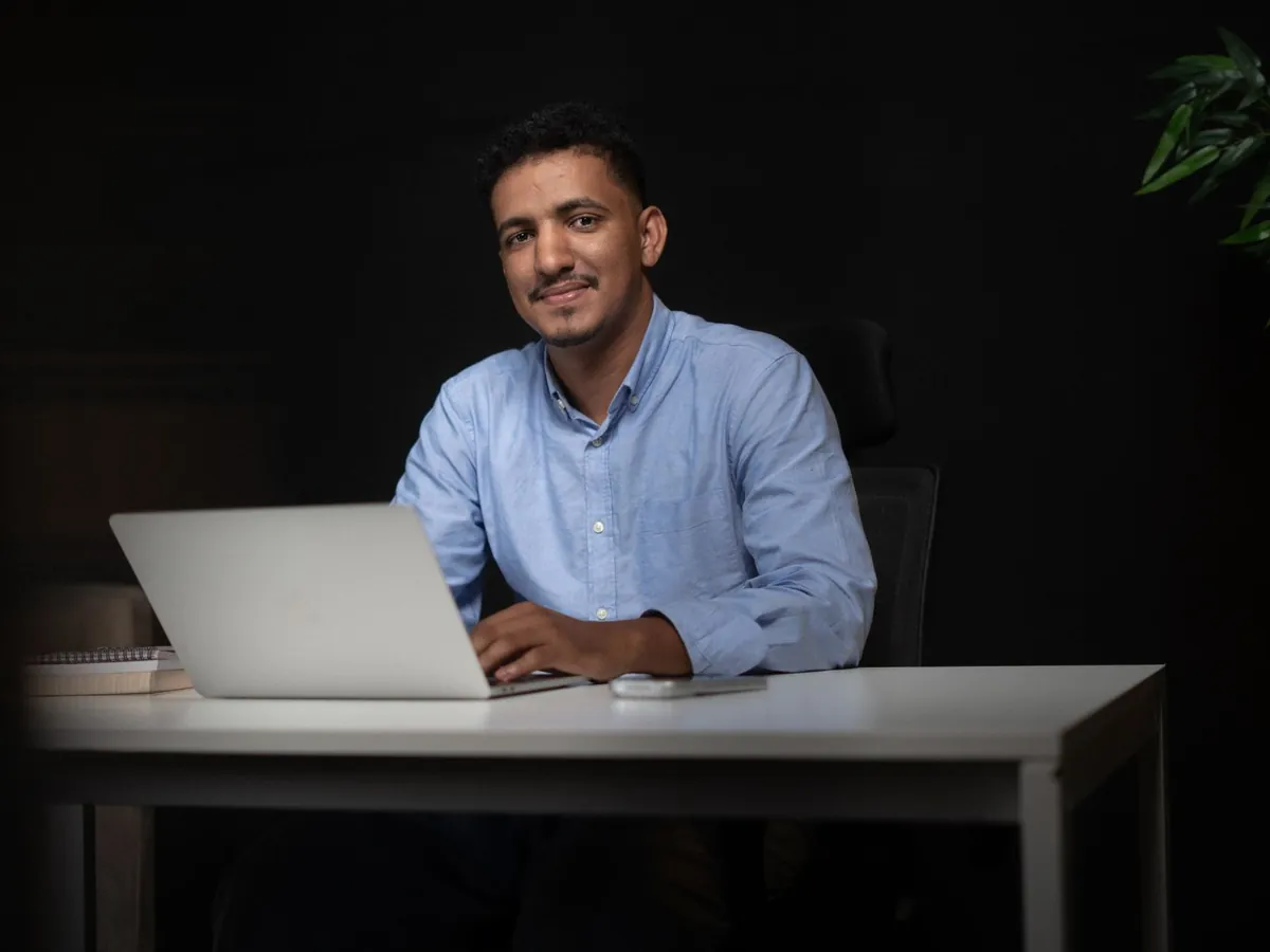 Homme d'affaires souriant, assis à son bureau devant un ordinateur portable