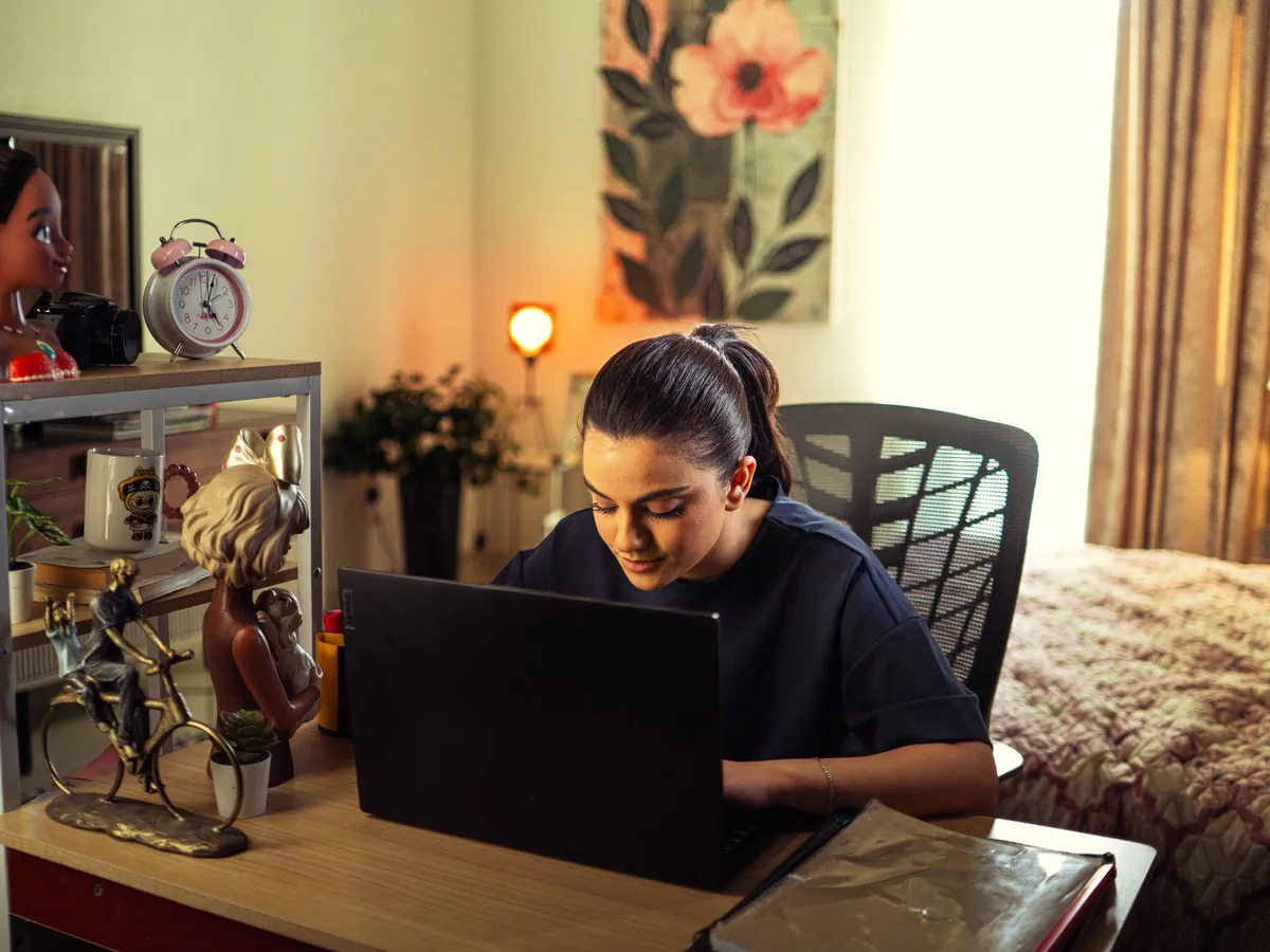 Femme concentrée sur son ordinateur portable dans un coin bureau chaleureux à domicile
